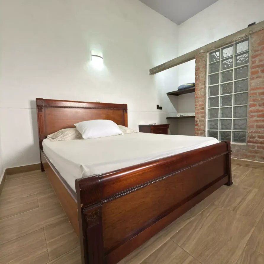 Acogedor dormitorio con cama doble de madera oscura, suelo de azulejos y ambiente tranquilo en Hotel Casa Encanto, Buga.