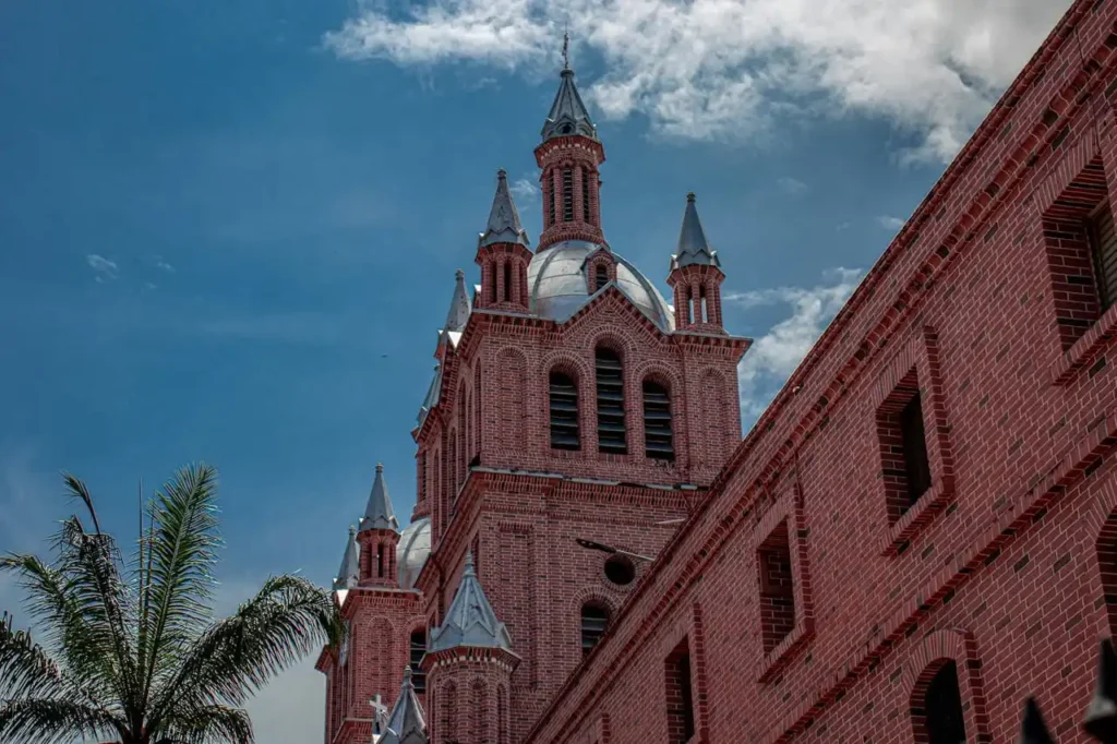 Hospedaje Semana Santa en Buga 2026: Vive la fe a un paso de la Basílica 7 Basílica del Señor de los Milagros en Buga, Valle del Cauca, con su imponente arquitectura de ladrillo rojo y cielo azul.